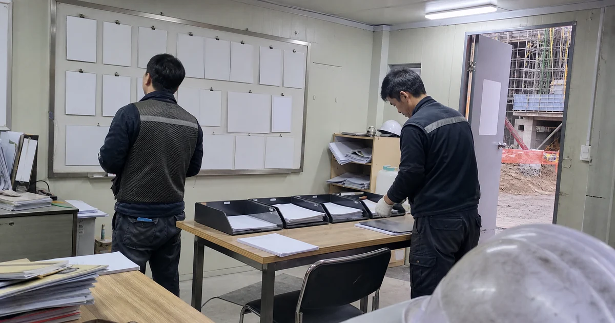 건설 현장 사무실에서 담당자들이 정산 서류를 절차별로 구분하는 모습