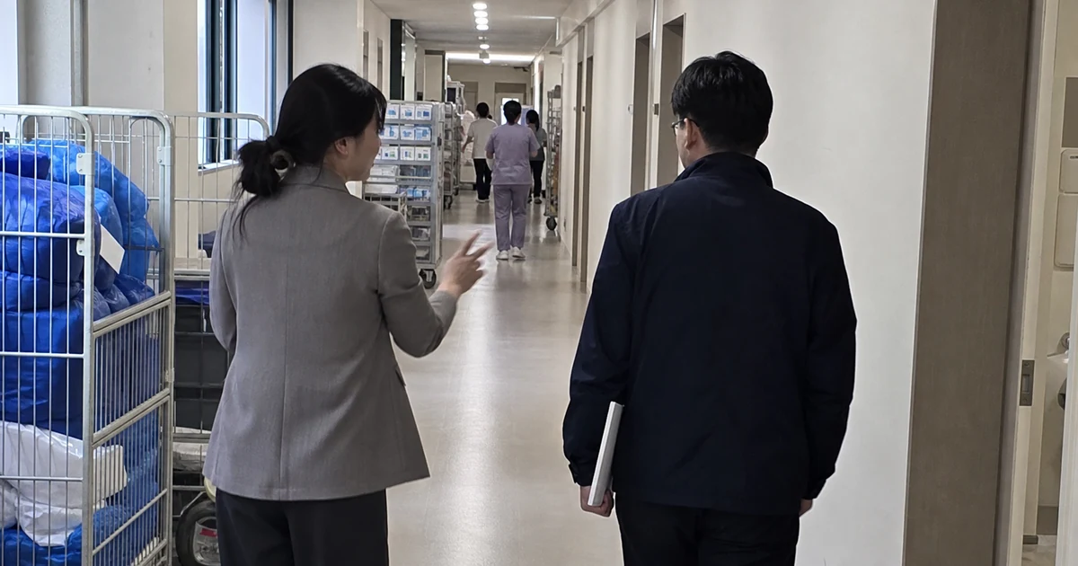 병원 직원 전용 통로에서 인사담당자가 외부 조사자에게 조사 대상 부서와 이동 동선을 설명하는 모습