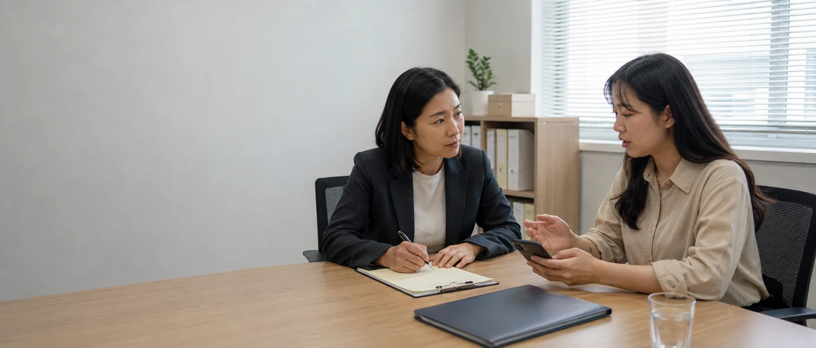 직장 내 성희롱 피해 근로자가 상담 담당자에게 휴대전화 자료를 보여 주며 설명하는 모습